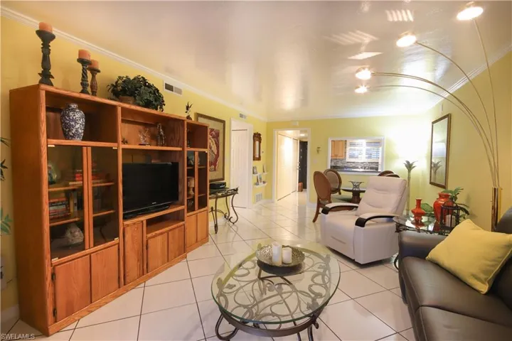 Living room featuring crown molding and light tile patterned flooring