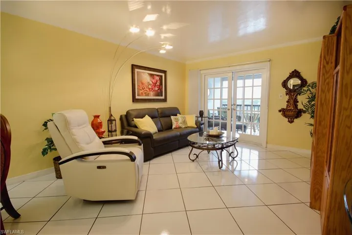 Living room featuring crown molding, french doors, and light tile patterned flooring