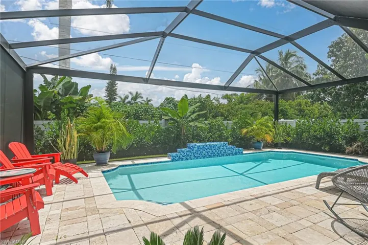 View of pool with a covered lanai space for outdoor entertaining with plenty of seating and lush landscaping for privacy