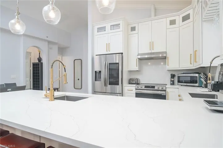 Kitchen featuring tasteful backsplash, pendant lighting, sink, appliances with stainless steel finishes, and lofted ceiling. Bar seating and open floorplan is great for entertaining.