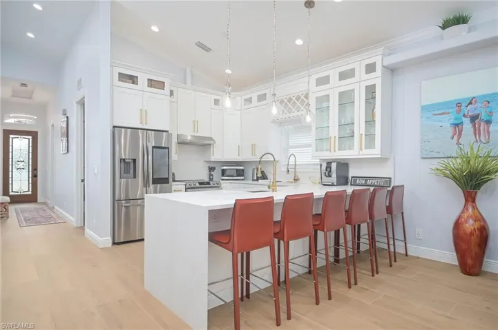 Kitchen featuring white cabinetry, decorative light fixtures, light hardwood / wood-style flooring, and appliances with stainless steel finishes