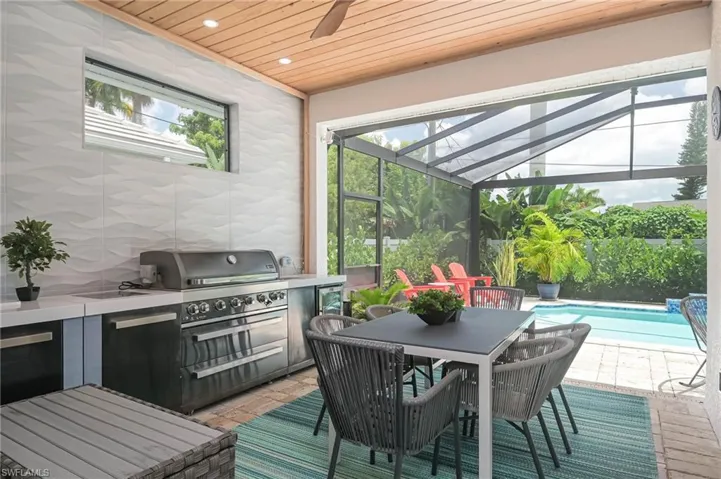 Custom outdoor kitchen withwood ceiling and picture screened-in lanai