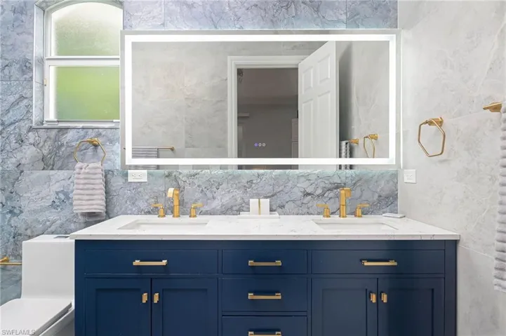 Primary Bathroom featuring decorative backsplash, tile walls, and double vanity