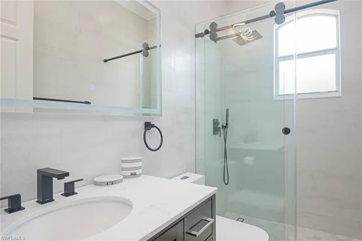 Bathroom with a shower with custom shower door, toilet, and vanity