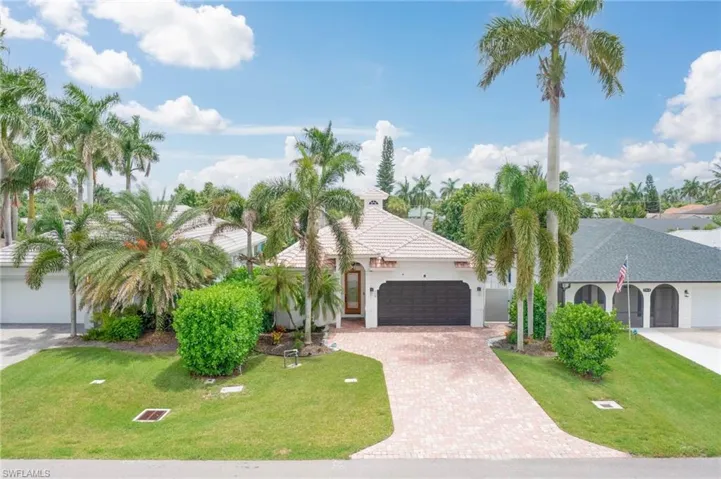 Contemporary home featuring a 2 car garage, tile roof, paved driveway, and lush landscaping