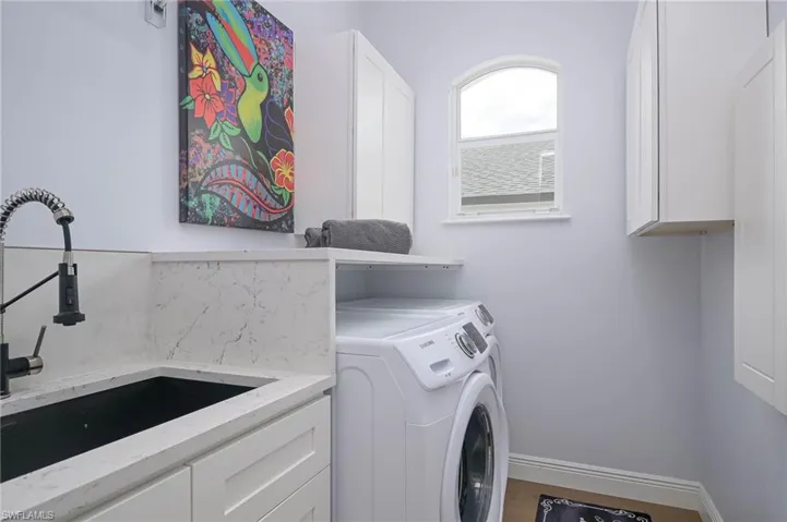 Laundry room featuring sink, cabinets, washer and dryer, and new floors