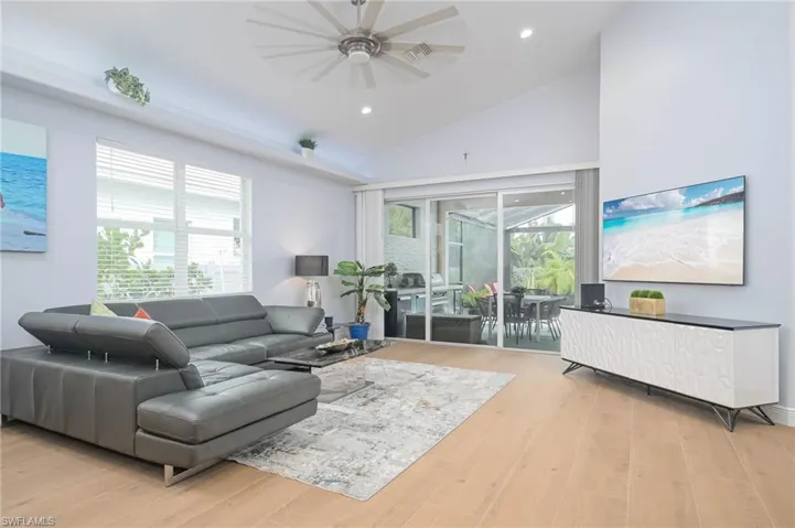 Living room with lofted ceiling, light hardwood / wood-style floors, and ceiling fan