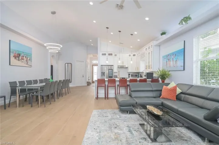 Living room with high vaulted ceiling, sink, and light hardwood / wood-style flooring