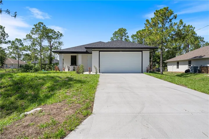 View of front of property with driveway, a garage, a front lawn, stucco siding, and roof with shingles