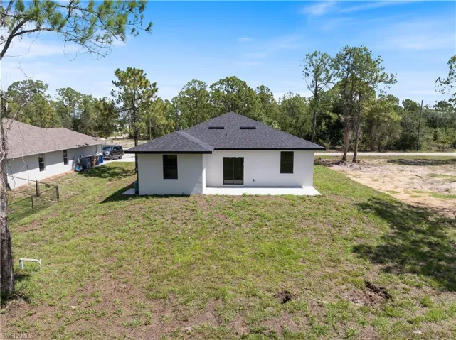 Back of house featuring stucco siding, a shingled roof, and a patio area