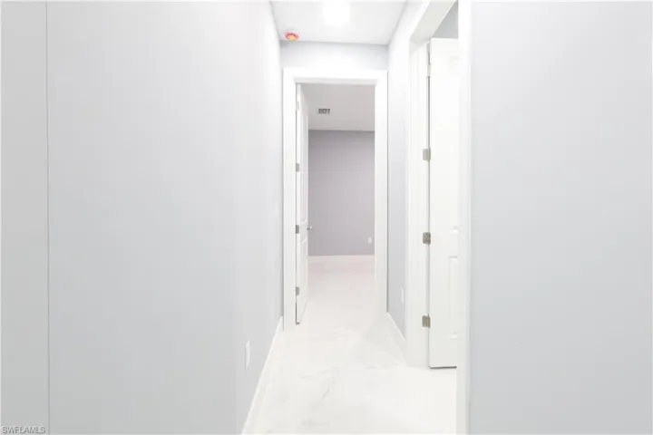 Corridor featuring baseboards and light marble finish flooring