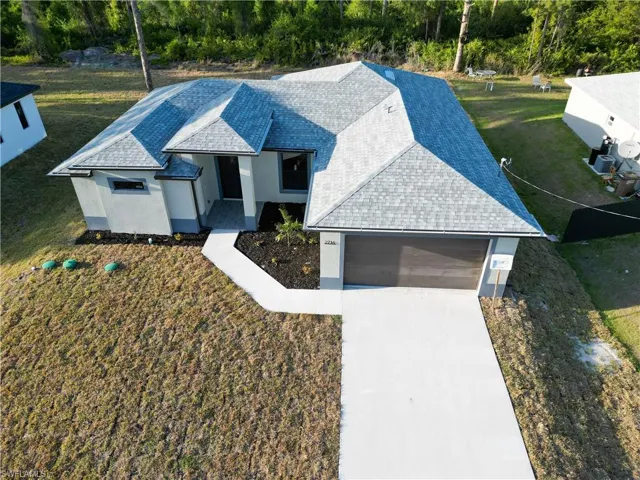 View of front of house featuring driveway, a shingled roof, an attached garage, stucco siding, and a front yard