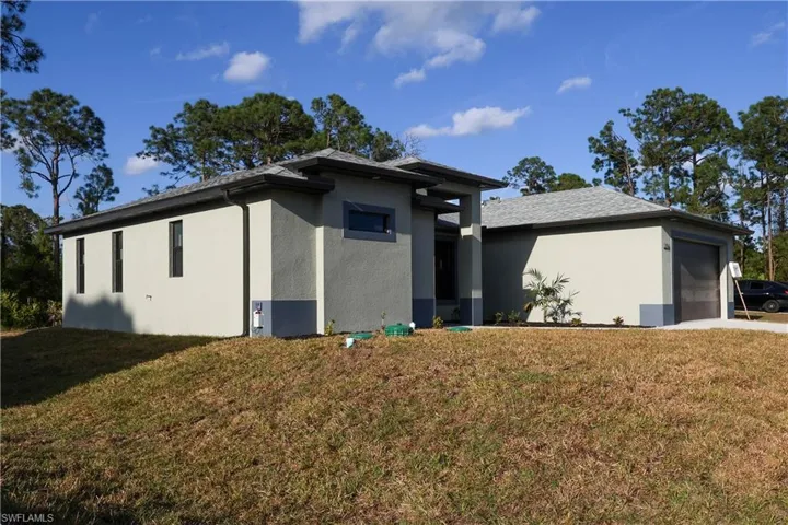 View of front of house with a garage, stucco siding, and a front lawn