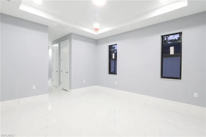 Empty room with a tray ceiling and marble finish floors
