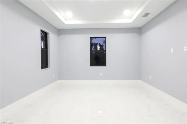 Spare room with marble look tiles, a raised ceiling, and recessed lighting