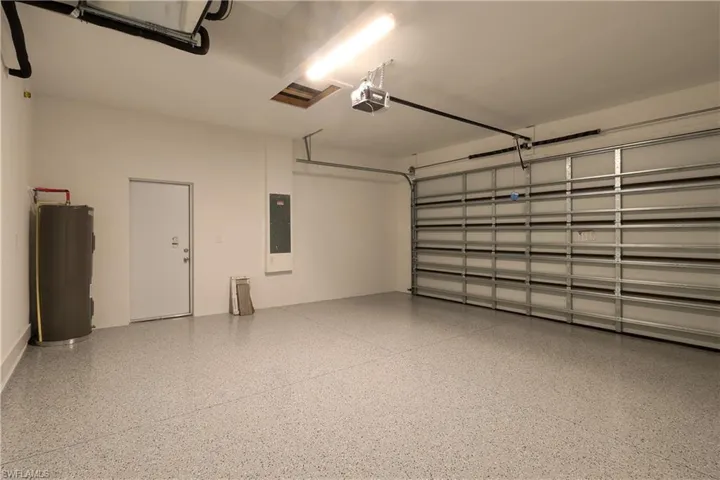 Garage with water heater, a garage door opener, and electric panel