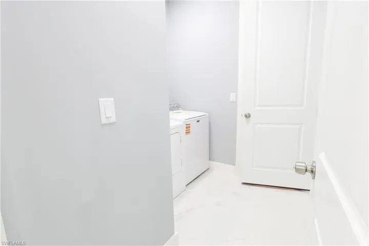 Washroom featuring washing machine and clothes dryer and light marble finish floors
