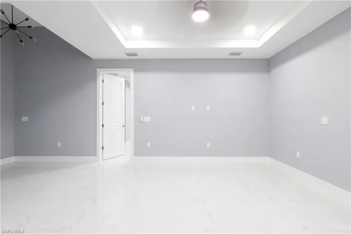 Empty room featuring a tray ceiling and marble finish floors