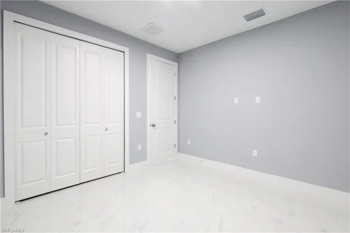 Unfurnished bedroom with a closet and marble finish floors