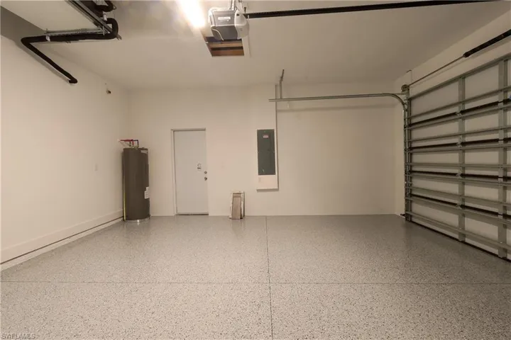 Garage with water heater, electric panel, and a garage door opener
