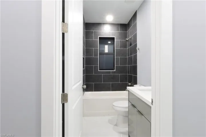 Full bath with vanity, marble look tile flooring, and bathtub / shower combination
