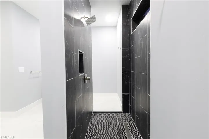 Full bath with tiled shower and baseboards