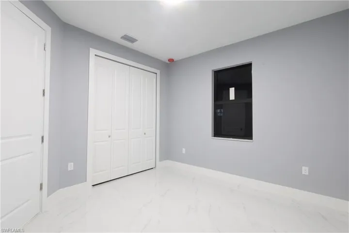 Unfurnished bedroom featuring light marble finish flooring and a closet
