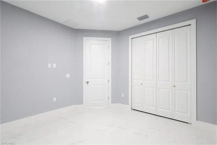 Unfurnished bedroom featuring light marble finish flooring and a closet