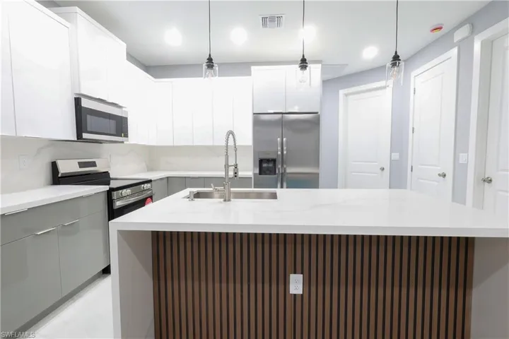 Kitchen with stainless steel appliances, a kitchen island with sink, modern cabinets, gray cabinets, and recessed lighting