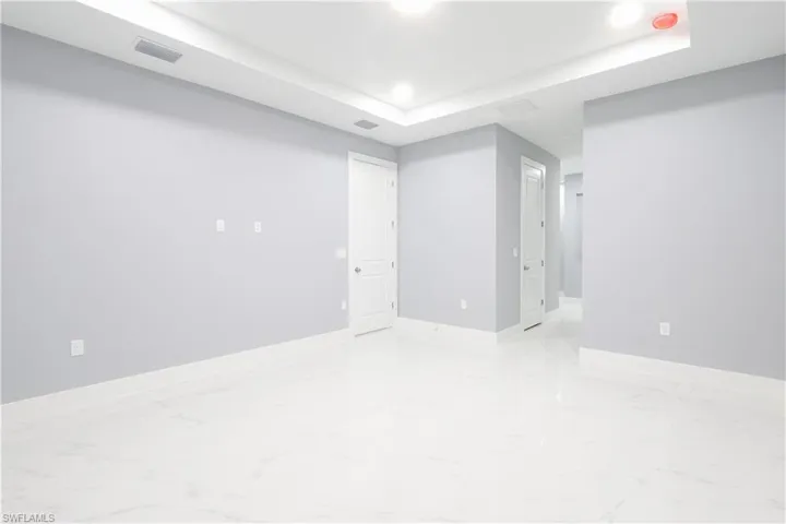 Unfurnished room featuring light marble finish floors and a raised ceiling