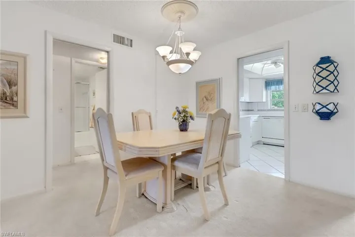 Dining room with a chandelier, light colored carpet, and a textured ceiling
