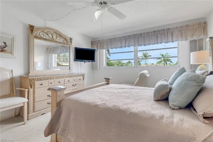 Bedroom featuring light colored carpet, a textured ceiling, and a ceiling fan