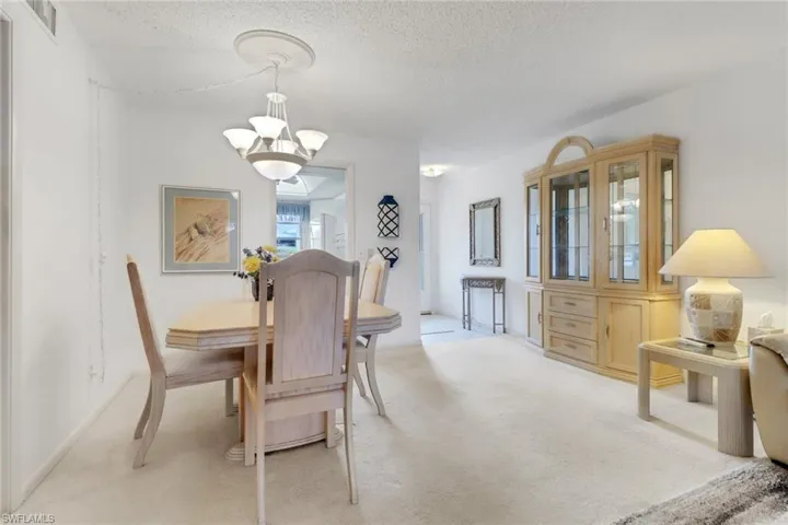 Dining room featuring light carpet, a chandelier, and a textured ceiling