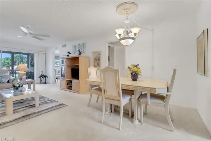 Dining room with light colored carpet, a chandelier, a textured ceiling, and a ceiling fan