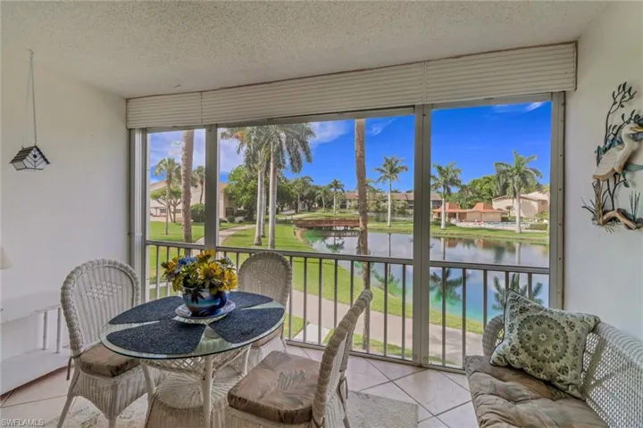 Sunroom featuring a water view, tile patterned floors, a textured ceiling, and a residential view