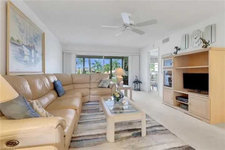 Carpeted living room with a ceiling fan, plenty of natural light, and a textured ceiling