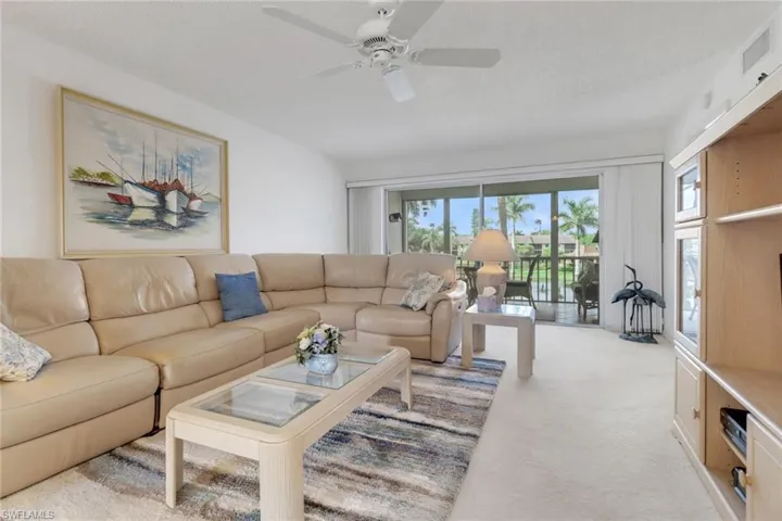 Living area featuring light carpet, a ceiling fan, and a textured ceiling