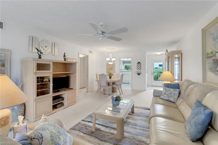 Living room with a ceiling fan, a textured ceiling, and a chandelier