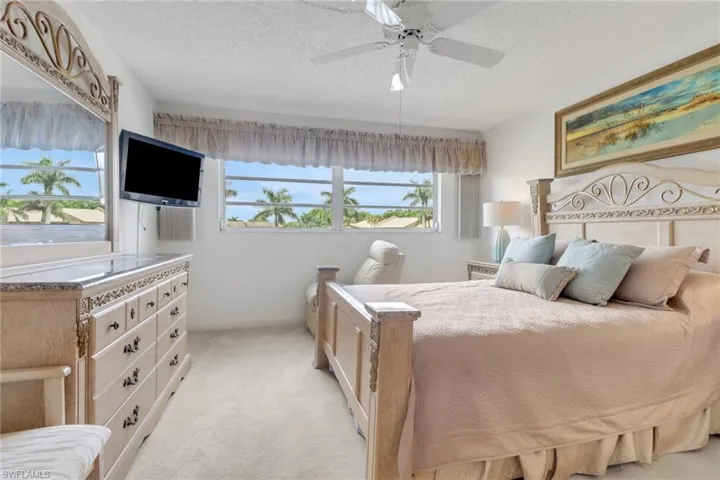 Bedroom featuring a textured ceiling, light colored carpet, and ceiling fan