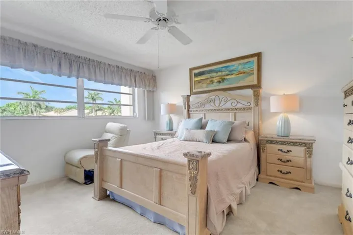 Bedroom with light colored carpet, a textured ceiling, and a ceiling fan