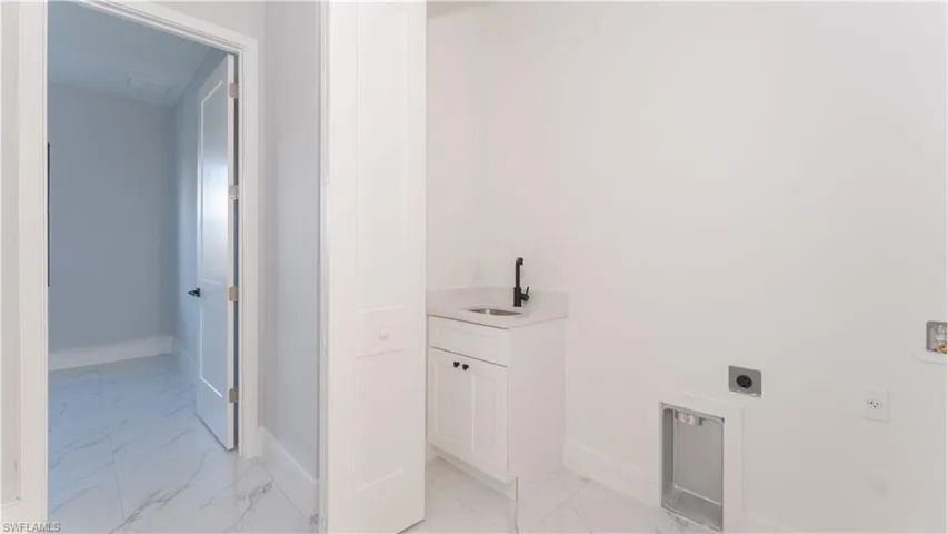 Clothes washing area featuring electric dryer hookup and sink