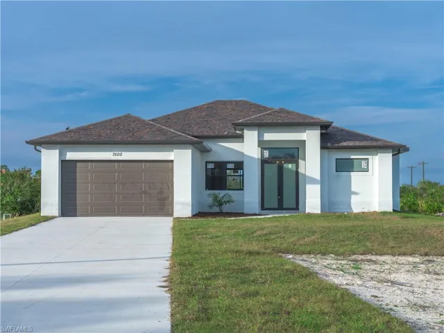 View of front of property featuring a garage and a front lawn