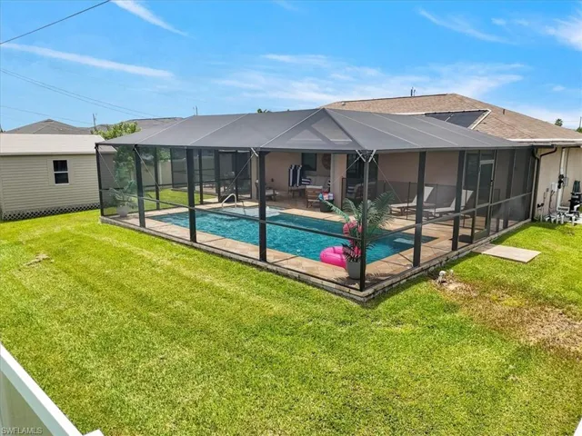 Back of house with a patio area, a yard, and glass enclosure