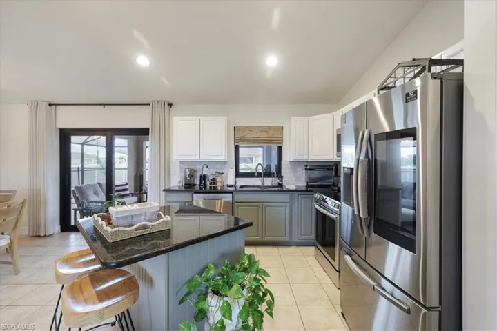 Kitchen with stainless steel appliances, light tile patterned floors, a kitchen island, backsplash, and recessed lighting