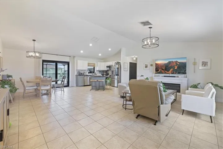 Living area with a chandelier, light tile patterned flooring, vaulted ceiling, and a fireplace