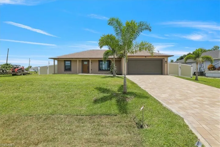 Ranch-style house featuring decorative driveway, a garage, and stucco siding