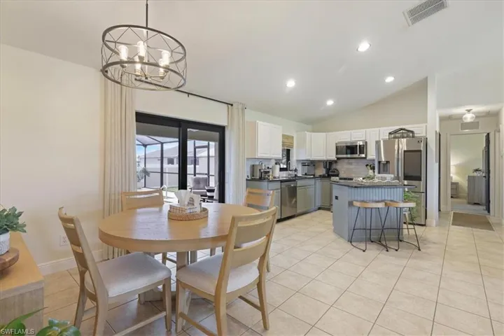 Dining space featuring vaulted ceiling, recessed lighting, light tile patterned floors, and a chandelier