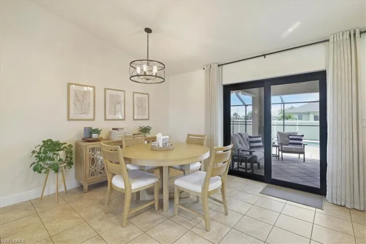 Dining space with light tile patterned floors, a chandelier, and lofted ceiling