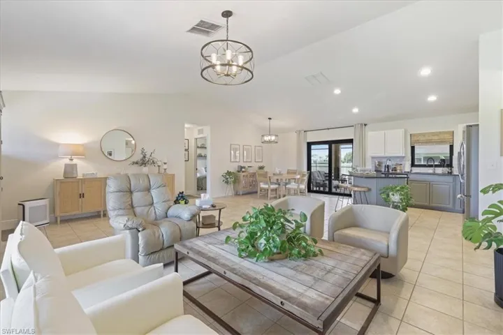 Living room with a chandelier, lofted ceiling, light tile patterned floors, and recessed lighting