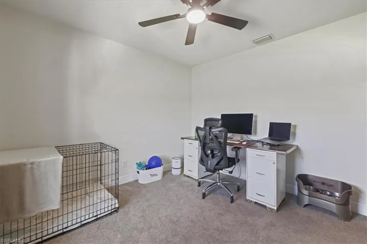Carpeted office with a ceiling fan and baseboards